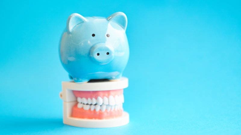 A blue piggy bank sitting on top of mock dentures